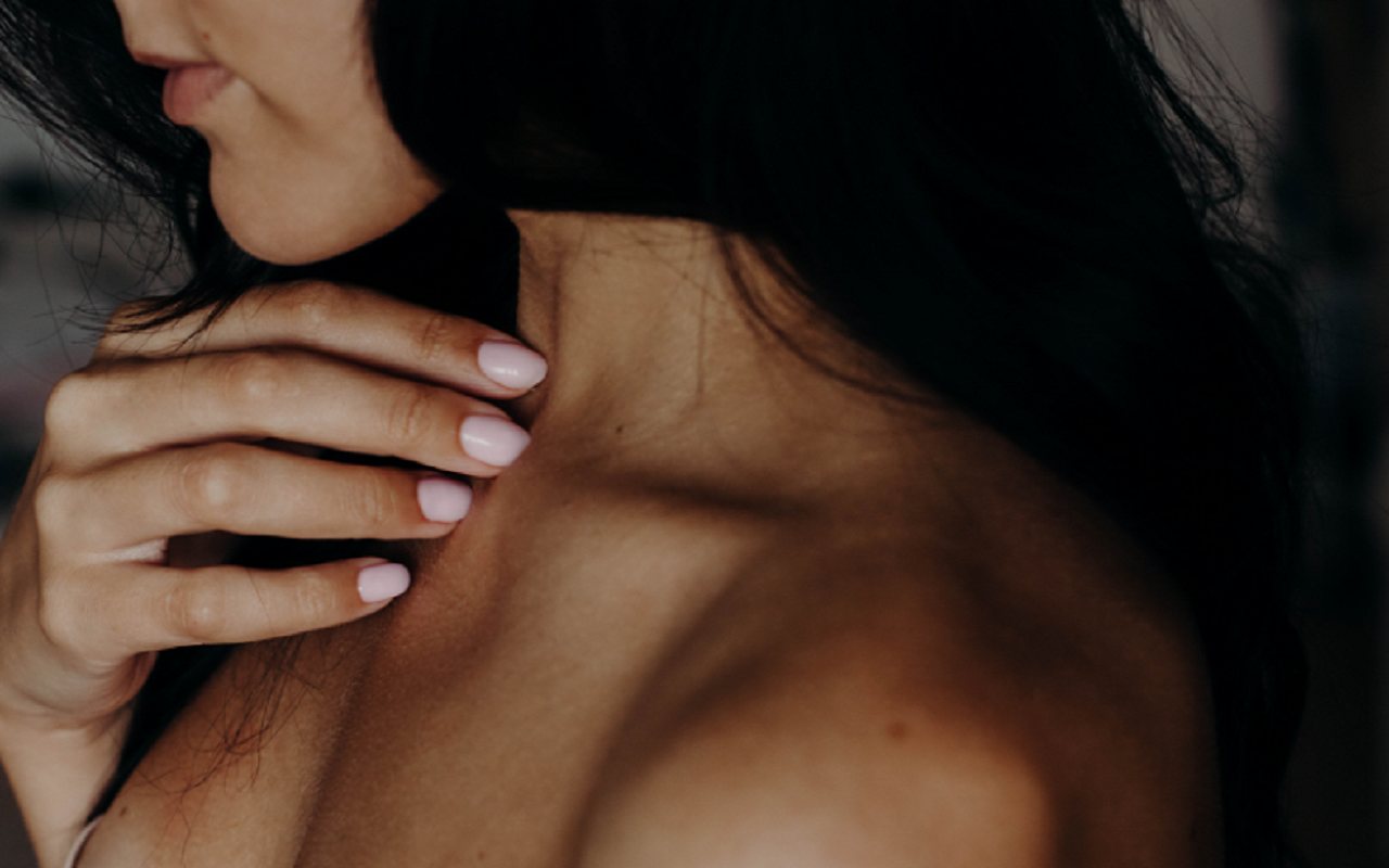 Kobieta dotykająca palcami swojej szyi
